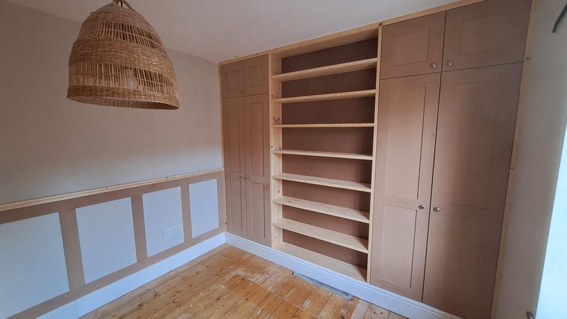 Full-width bedroom storage with wardrobes and open shelving