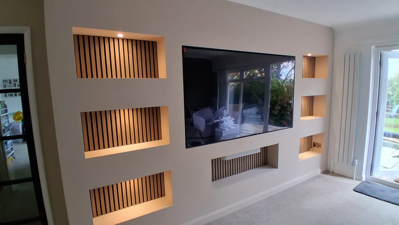 A bespoke media wall with lit oak-slatted niches flanking a wall-mounted TV
